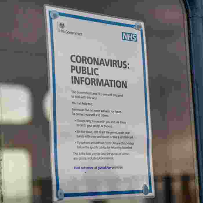 An A4 print out displayed in a door window with NHS information about coronavirus