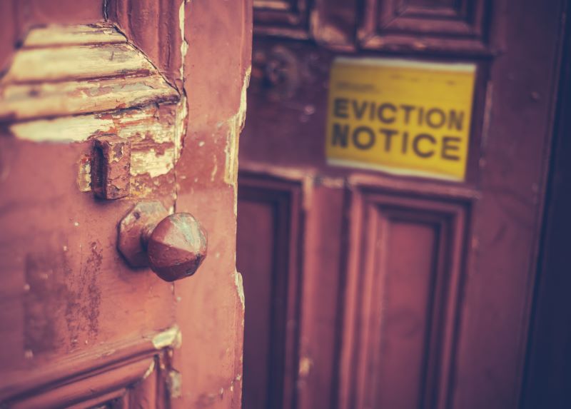Yellow eviction notice on wooden front door