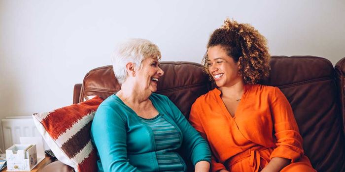 Two women laughing together on a sofa